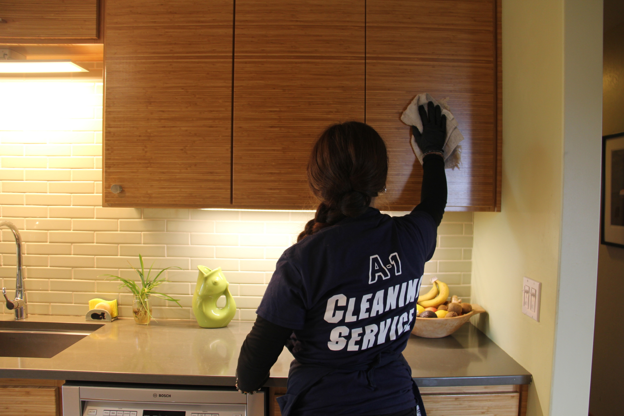 A‑1 Cleaning Service technician wiping down kitchen cabinets during a residential home cleaning in Humboldt County.