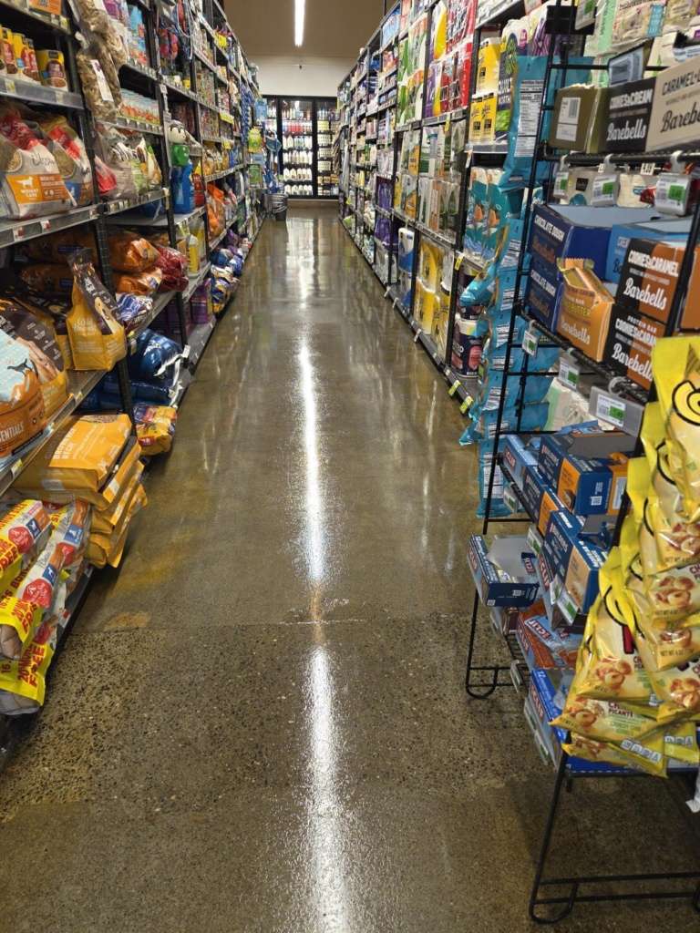 Store aisle with tall shelves on both sides, packed with colorful bags and boxes, seen from the center toward the back.
